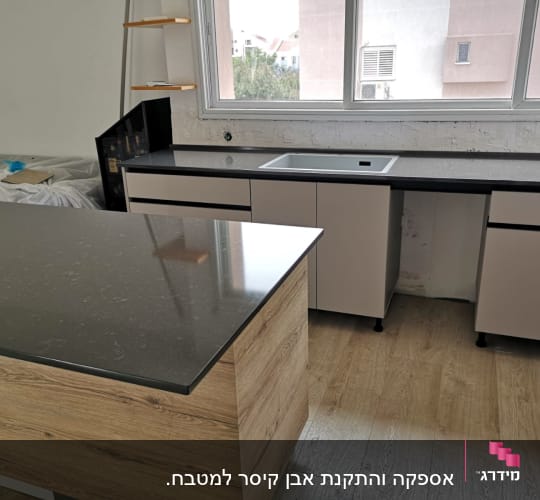 משטח שיש כהה במטבח מודרני עם ארונות בהירים